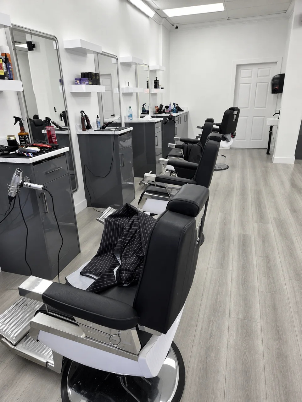 Row of black barber chairs inside the bright Bladez Affair shop